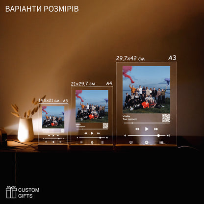 Apple Music poster size options displayed with custom photos and song titles on a stylish table setup.